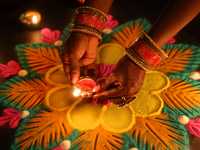 A Hindu devotee places a diya (small clay lamp) by a rangoli design during the festival of Diwali at a Hindu temple in Toronto, Ontario, Can...