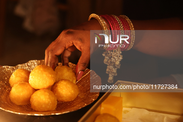 A Hindu devotee places ladoos (a traditional Indian sweet) in a bowl during the festival of Diwali at a Hindu temple in Toronto, Ontario, Ca...