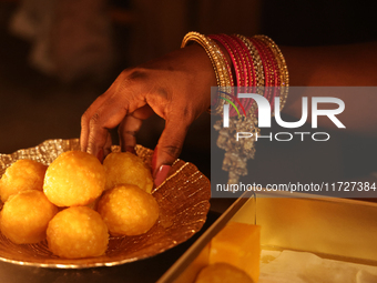 A Hindu devotee places ladoos (a traditional Indian sweet) in a bowl during the festival of Diwali at a Hindu temple in Toronto, Ontario, Ca...