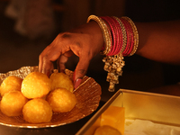 A Hindu devotee places ladoos (a traditional Indian sweet) in a bowl during the festival of Diwali at a Hindu temple in Toronto, Ontario, Ca...