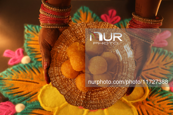 A Hindu devotee holds a bowl of laddus (a traditional Indian sweet) during the festival of Diwali at a Hindu temple in Toronto, Ontario, Can...