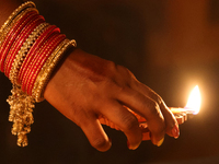 A Hindu devotee places a diya (small clay lamp) by a rangoli design during the festival of Diwali at a Hindu temple in Toronto, Ontario, Can...