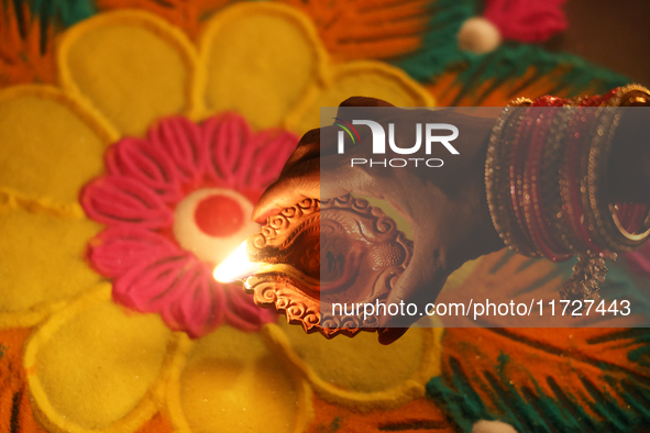 A Hindu devotee places a diya (small clay lamp) by a rangoli design during the festival of Diwali at a Hindu temple in Toronto, Ontario, Can...