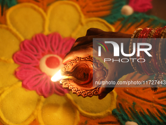 A Hindu devotee places a diya (small clay lamp) by a rangoli design during the festival of Diwali at a Hindu temple in Toronto, Ontario, Can...