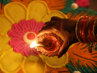 A Hindu devotee places a diya (small clay lamp) by a rangoli design during the festival of Diwali at a Hindu temple in Toronto, Ontario, Can...