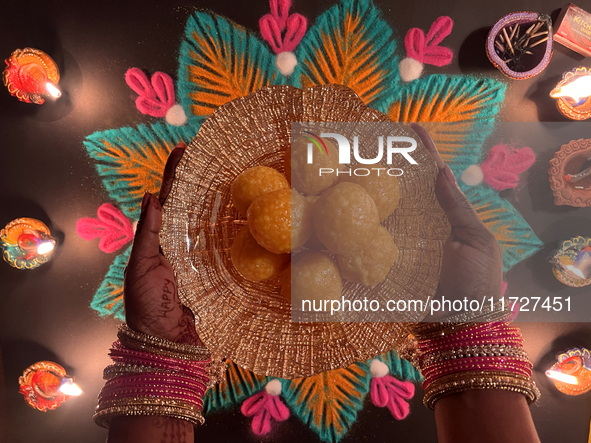 A Hindu devotee holds a bowl of laddus (a traditional Indian sweet) during the festival of Diwali at a Hindu temple in Toronto, Ontario, Can...