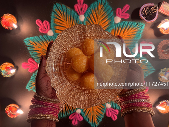 A Hindu devotee holds a bowl of laddus (a traditional Indian sweet) during the festival of Diwali at a Hindu temple in Toronto, Ontario, Can...