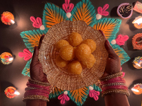 A Hindu devotee holds a bowl of laddus (a traditional Indian sweet) during the festival of Diwali at a Hindu temple in Toronto, Ontario, Can...