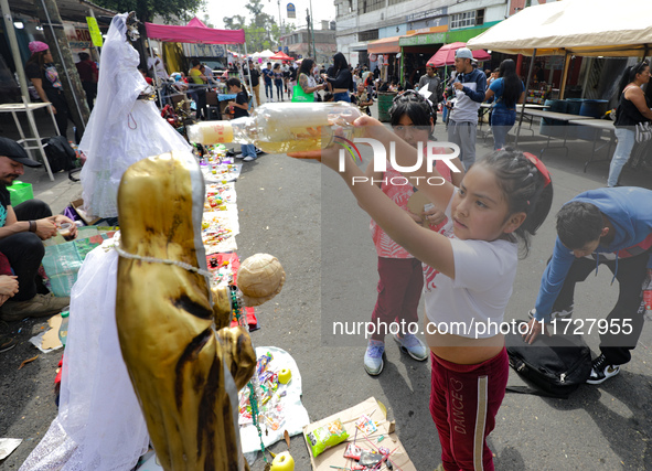 A girl blesses an image of Santa Muerte with tequila outside the Altar of Santa Muerte located on Alfareria Street in the Tepito neighborhoo...