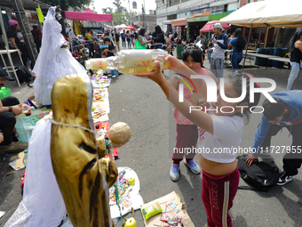 A girl blesses an image of Santa Muerte with tequila outside the Altar of Santa Muerte located on Alfareria Street in the Tepito neighborhoo...