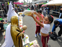 A girl blesses an image of Santa Muerte with tequila outside the Altar of Santa Muerte located on Alfareria Street in the Tepito neighborhoo...