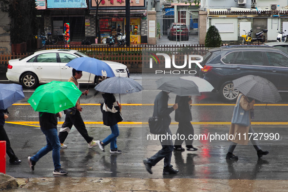 Pedestrians hold umbrellas as they walk on a street in Shanghai, China, on November 1, 2024. 