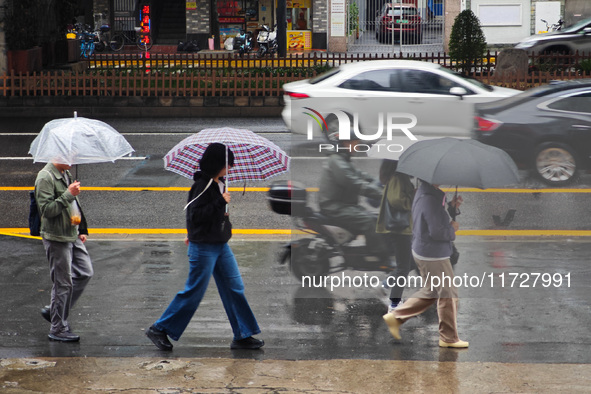 Pedestrians hold umbrellas as they walk on a street in Shanghai, China, on November 1, 2024. 