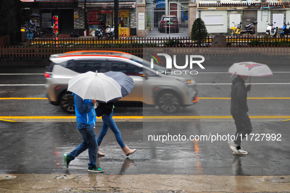 Pedestrians hold umbrellas as they walk on a street in Shanghai, China, on November 1, 2024. 