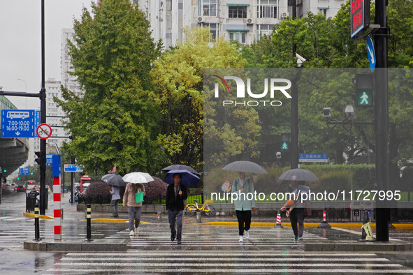 Pedestrians hold umbrellas as they walk on a street in Shanghai, China, on November 1, 2024. 