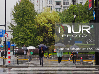 Pedestrians hold umbrellas as they walk on a street in Shanghai, China, on November 1, 2024. (