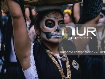 A woman wearing a traditional Mexican dress and with her face painted as a skull takes part in a parade known locally as a 'comparsa,' walki...