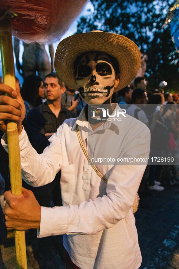 A boy with his face painted as a skull takes part in a parade known locally as a 'comparsa,' walking the main streets of Oaxaca City as part...