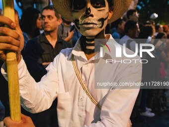 A boy with his face painted as a skull takes part in a parade known locally as a 'comparsa,' walking the main streets of Oaxaca City as part...