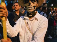 A boy with his face painted as a skull takes part in a parade known locally as a 'comparsa,' walking the main streets of Oaxaca City as part...