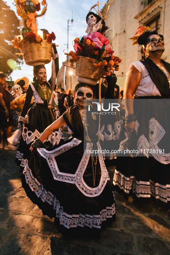 A woman wearing a traditional Mexican dress and with her face painted as a skull takes part in a parade known locally as a 'comparsa,' walki...