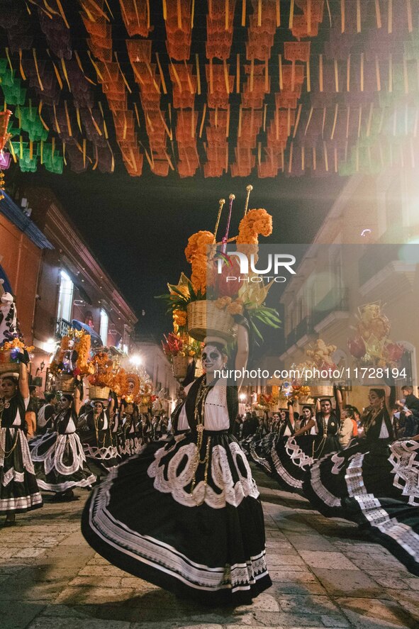 A woman wearing a traditional Mexican dress and with her face painted as a skull takes part in a parade known locally as a 'comparsa,' walki...