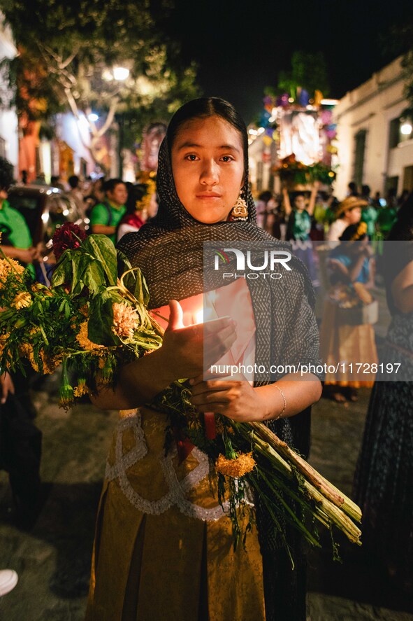 A woman wearing a traditional Mexican dress takes part in a parade known locally as a 'comparsa,' walking the main streets of Oaxaca City as...