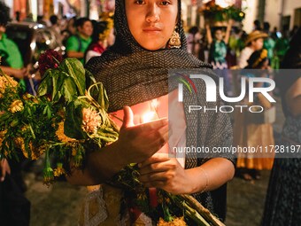 A woman wearing a traditional Mexican dress takes part in a parade known locally as a 'comparsa,' walking the main streets of Oaxaca City as...