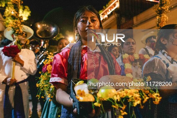 A woman wearing a traditional Mexican dress takes part in a parade known locally as a 'comparsa,' walking the main streets of Oaxaca City as...