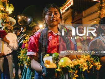 A woman wearing a traditional Mexican dress takes part in a parade known locally as a 'comparsa,' walking the main streets of Oaxaca City as...