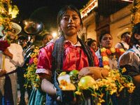 A woman wearing a traditional Mexican dress takes part in a parade known locally as a 'comparsa,' walking the main streets of Oaxaca City as...