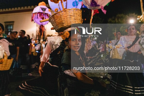 A woman wearing a traditional Mexican dress and with her face painted as a skull takes part in a parade known locally as a 'comparsa,' walki...