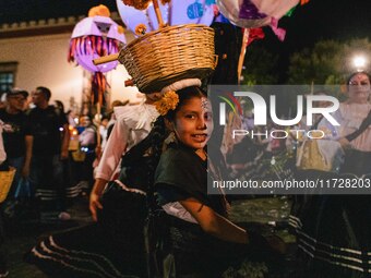 A woman wearing a traditional Mexican dress and with her face painted as a skull takes part in a parade known locally as a 'comparsa,' walki...