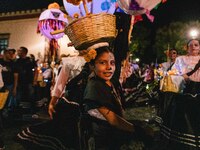 A woman wearing a traditional Mexican dress and with her face painted as a skull takes part in a parade known locally as a 'comparsa,' walki...