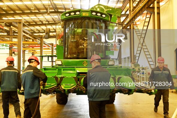 Construction workers assemble agricultural machinery at Jiufang Taihe International Heavy Industries (Qingdao) Co., LTD., Hongshiya Street,...