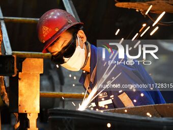 A construction worker builds petrochemical equipment parts at Lanshi Heavy Machinery Co., LTD., Hongshiya Street, in Qingdao, China, on Octo...