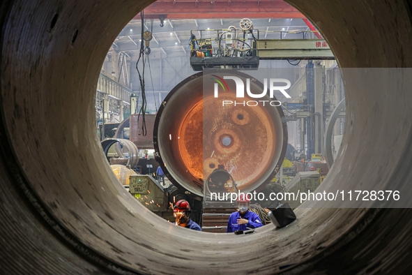 An employee works on a large pressure vessel customized by an oil refinery at the production workshop of Qingdao Lanshi Heavy Machinery Equi...