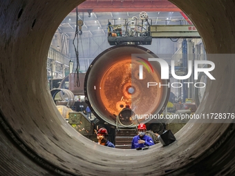 An employee works on a large pressure vessel customized by an oil refinery at the production workshop of Qingdao Lanshi Heavy Machinery Equi...