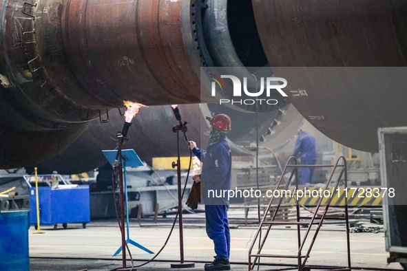 An employee works on a large pressure vessel customized by an oil refinery at the production workshop of Qingdao Lanshi Heavy Machinery Equi...