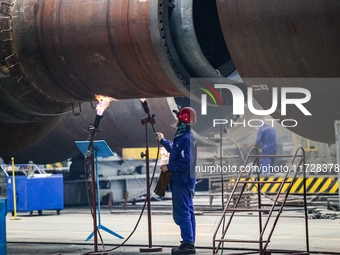 An employee works on a large pressure vessel customized by an oil refinery at the production workshop of Qingdao Lanshi Heavy Machinery Equi...