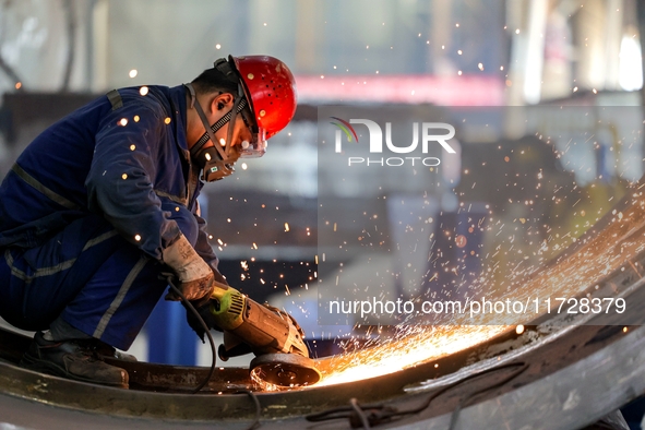 An employee works on a large pressure vessel customized by an oil refinery at the production workshop of Qingdao Lanshi Heavy Machinery Equi...