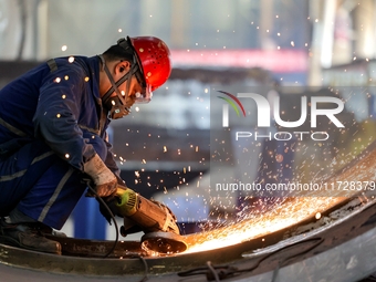 An employee works on a large pressure vessel customized by an oil refinery at the production workshop of Qingdao Lanshi Heavy Machinery Equi...