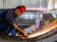 An employee works on a large pressure vessel customized by an oil refinery at the production workshop of Qingdao Lanshi Heavy Machinery Equi...