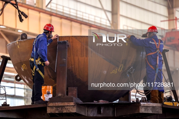 An employee works on a large pressure vessel customized by an oil refinery at the production workshop of Qingdao Lanshi Heavy Machinery Equi...