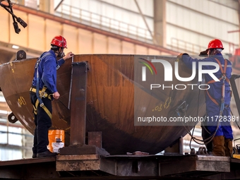 An employee works on a large pressure vessel customized by an oil refinery at the production workshop of Qingdao Lanshi Heavy Machinery Equi...