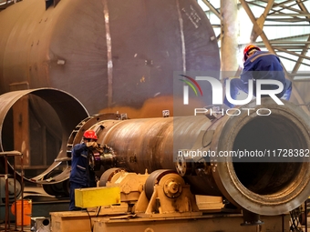 An employee works on a large pressure vessel customized by an oil refinery at the production workshop of Qingdao Lanshi Heavy Machinery Equi...