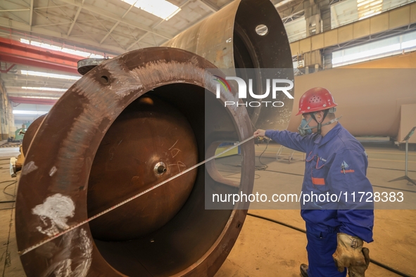 An employee works on a large pressure vessel customized by an oil refinery at the production workshop of Qingdao Lanshi Heavy Machinery Equi...