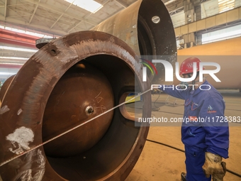 An employee works on a large pressure vessel customized by an oil refinery at the production workshop of Qingdao Lanshi Heavy Machinery Equi...