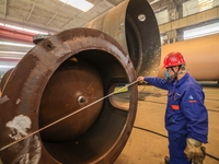 An employee works on a large pressure vessel customized by an oil refinery at the production workshop of Qingdao Lanshi Heavy Machinery Equi...