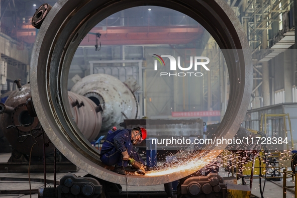 An employee works on a large pressure vessel customized by an oil refinery at the production workshop of Qingdao Lanshi Heavy Machinery Equi...